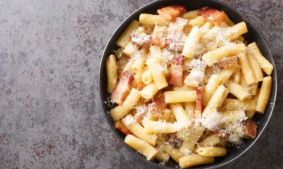 Un piatto di pasta alla gricia fumante, con guanciale croccante e abbondante pecorino romano.