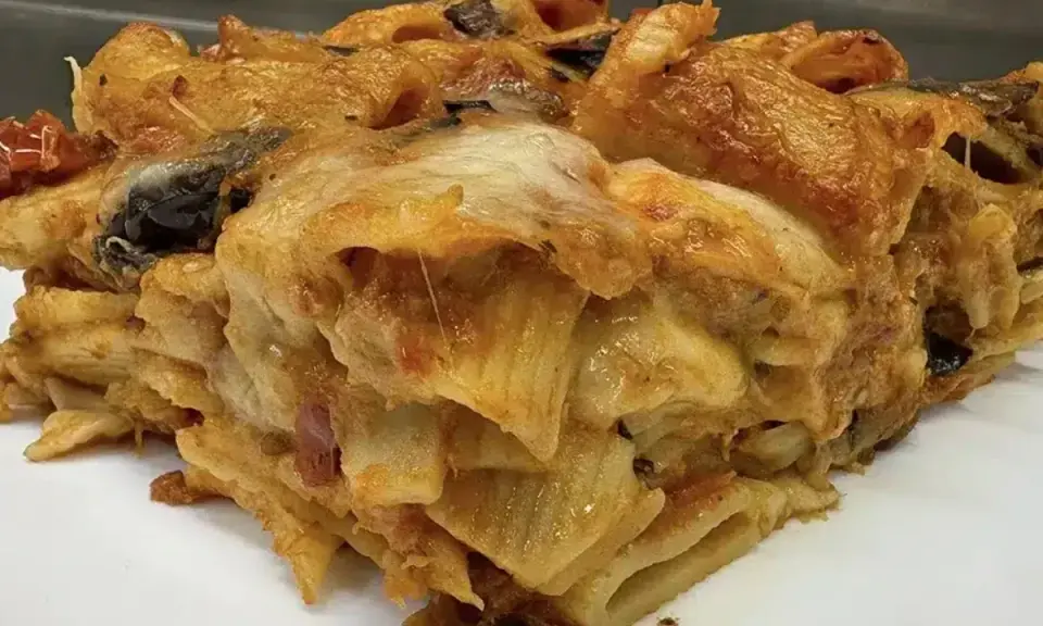 Una fetta di pasta al forno ricca e dorata, con strati di pasta, melanzane e formaggio filante.
