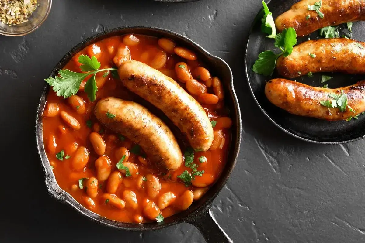 Salsiccia e fagioli in padella, un piatto rustico e saporito, con prezzemolo fresco a guarnire.