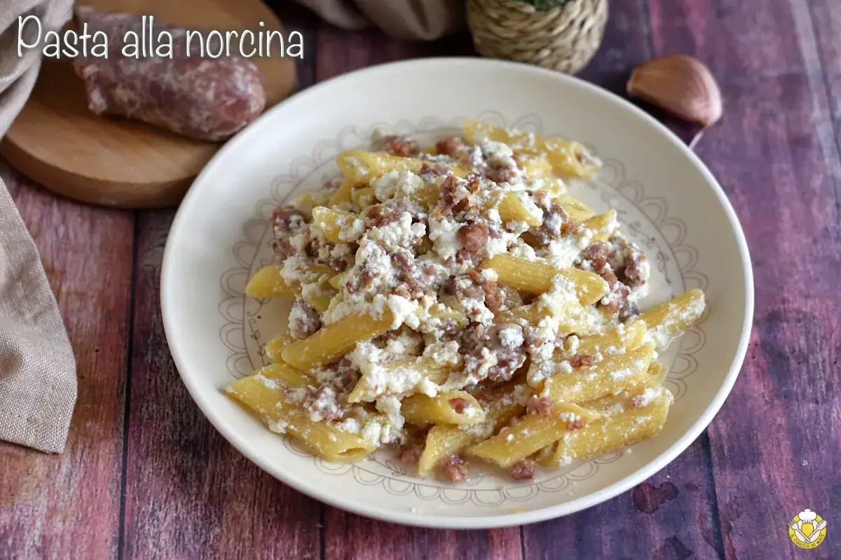 Piatto di pasta alla norcina con salsiccia sbriciolata e ricotta cremosa. Un classico della cucina umbra, pronto per essere gustato.