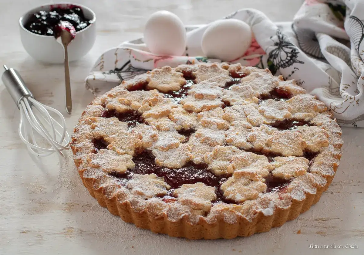 Una deliziosa crostata di marmellata, con decorazioni a fiore e spolverata di zucchero a velo, pronta per essere gustata.