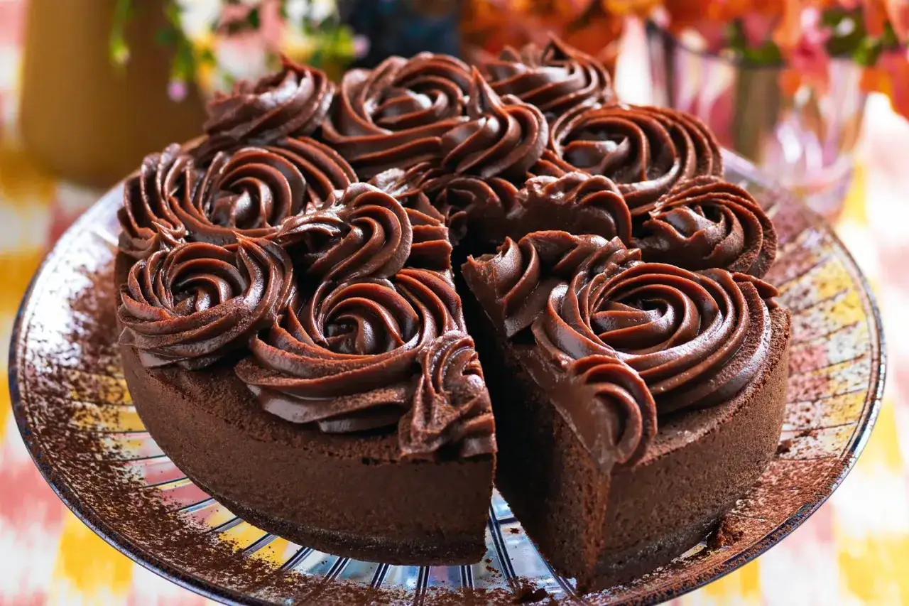 Una deliziosa torta al cioccolato, ricoperta da rosette di crema al cacao, con una fetta mancante che invita a un assaggio goloso.