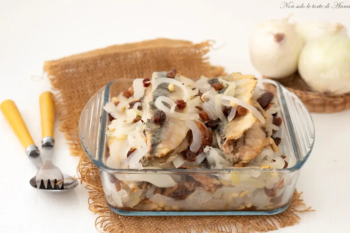 Sarde in saor in una pirofila di vetro, con cipolle, uvetta e pinoli. Un piatto tradizionale pronto per essere gustato.