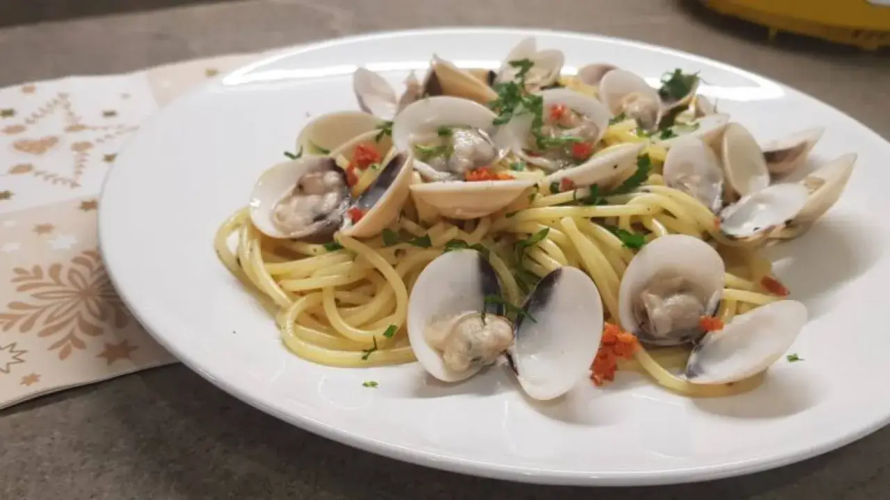 Spaghetti alle vongole surgelate, un piatto gustoso e veloce, con vongole aperte e prezzemolo tritato su pasta dorata.