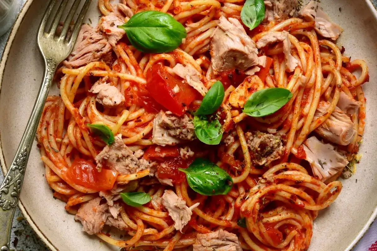 Spaghetti con tonno in scatola, pomodoro e basilico fresco. Un piatto semplice e gustoso, pronto in pochi minuti.