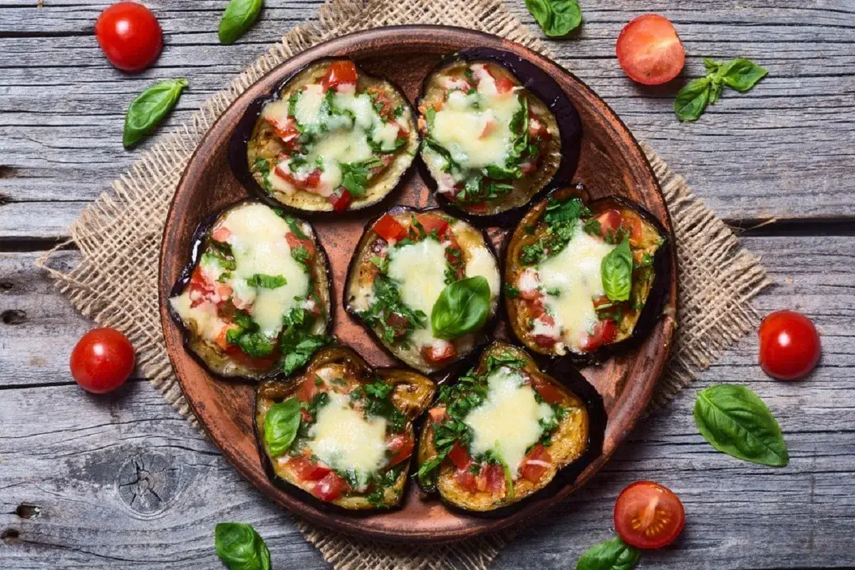 Fette di melanzane cotte al forno, condite con pomodoro, basilico e formaggio fuso, un piatto gustoso di melanzane alla pizzaiola.