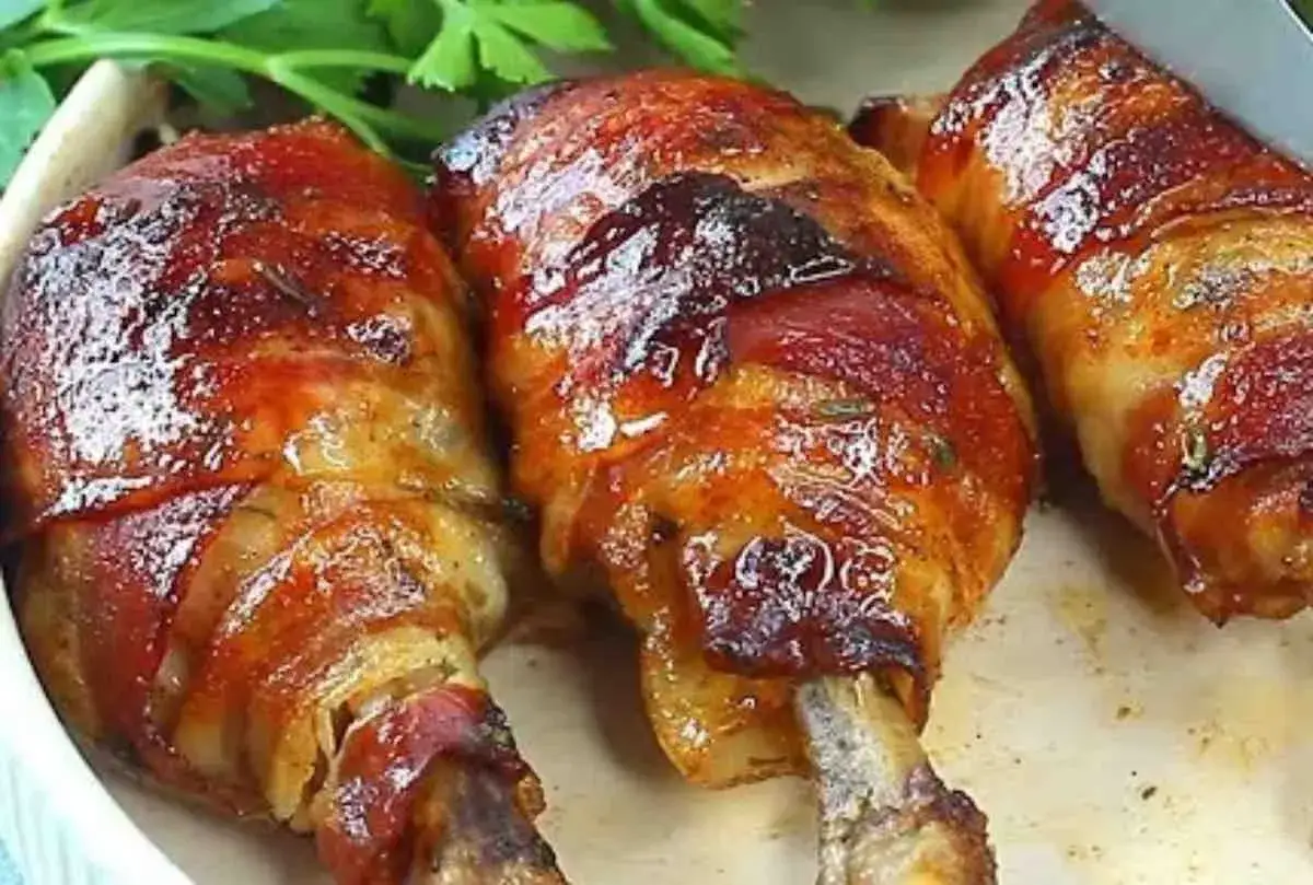 Sovracosce di pollo al forno avvolte in pancetta croccante, con erbe aromatiche e una glassatura lucida.