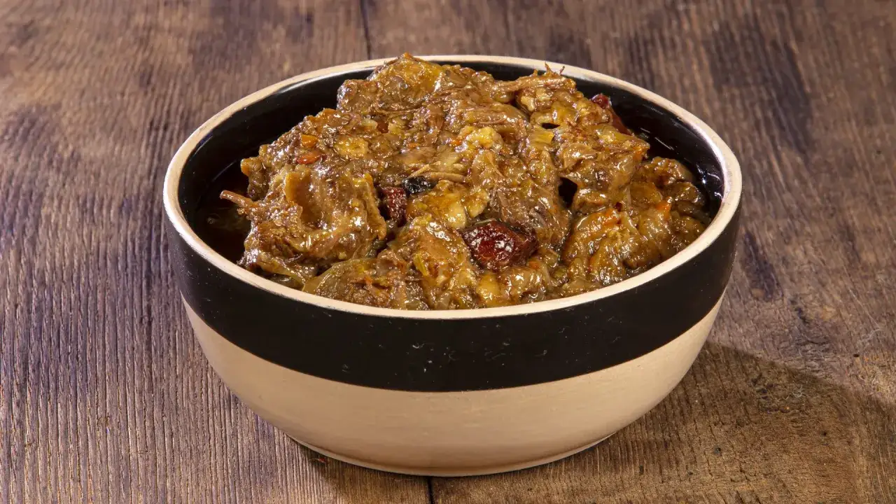 Una ciotola di ziti alla genovese, un piatto ricco e saporito con carne stufata e cipolle caramellate, pronto per essere gustato.
