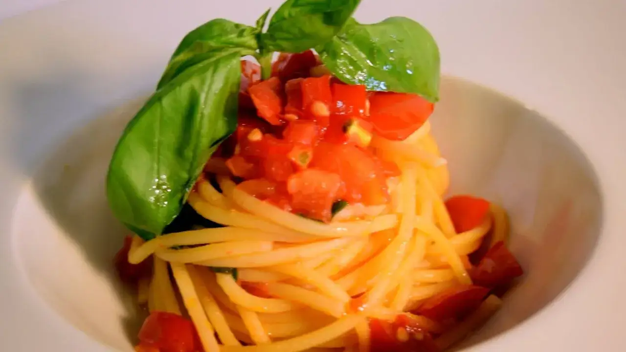 Spaghetti freschi conditi con un sugo di pomodorini succosi e basilico profumato, un classico piatto di pasta.
