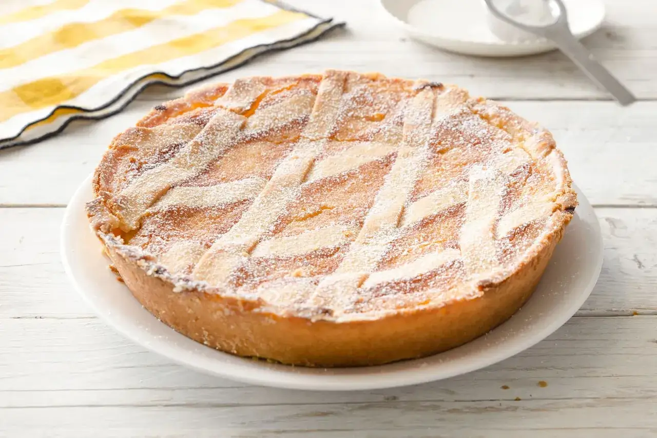 Pastiera napoletana pronta, un dolce tradizionale che mostra come si fa la pastiera con la sua crostata decorata a losanghe e spolverata di zucchero a velo.