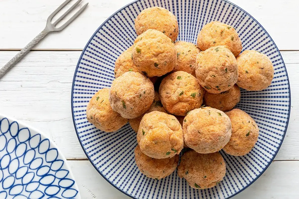 Un piatto pieno di dorate polpette di merluzzo, pronte per essere gustate.