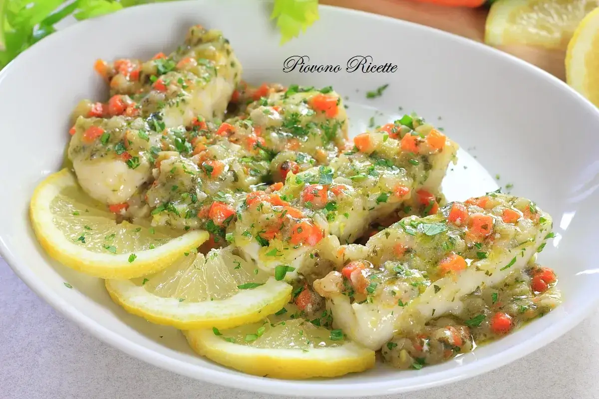 Delizioso merluzzo in padella, condito con verdure tritate e prezzemolo, servito con fette di limone.