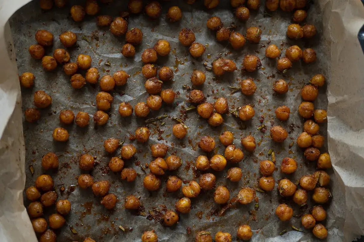 Ceci croccanti al forno, dorati e profumati, sparsi su carta da forno. Un'esplosione di gusto e texture.