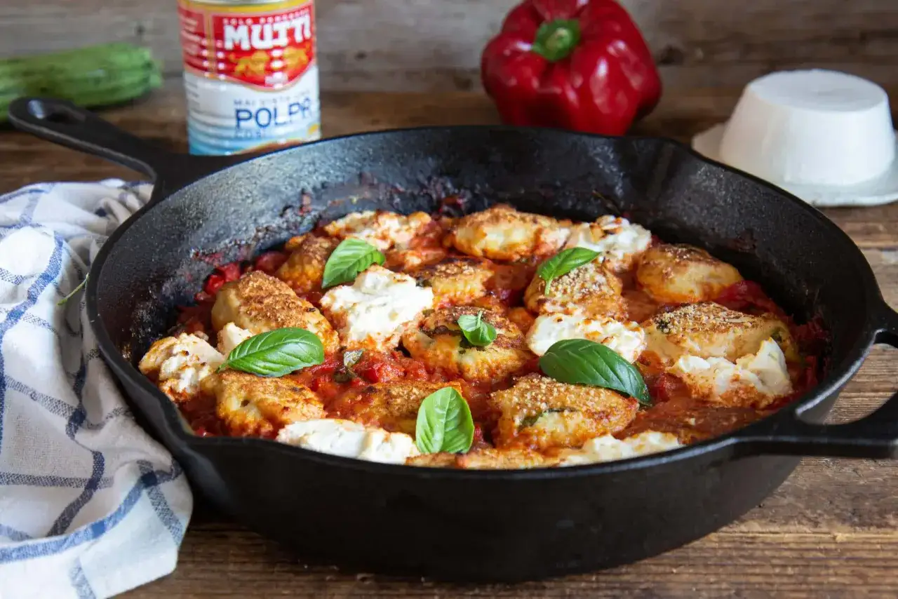 Polpette di pollo al sugo con ricotta e basilico, servite in padella. Ingredienti freschi e saporiti per un piatto invitante.