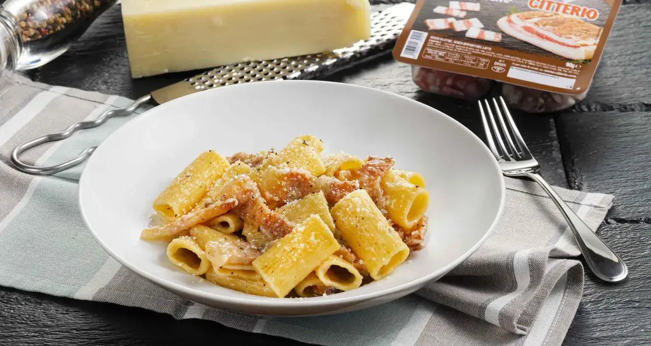Un piatto di pasta alla gricia fumante, con guanciale croccante e pecorino romano grattugiato. Ingredienti freschi e sapori autentici.