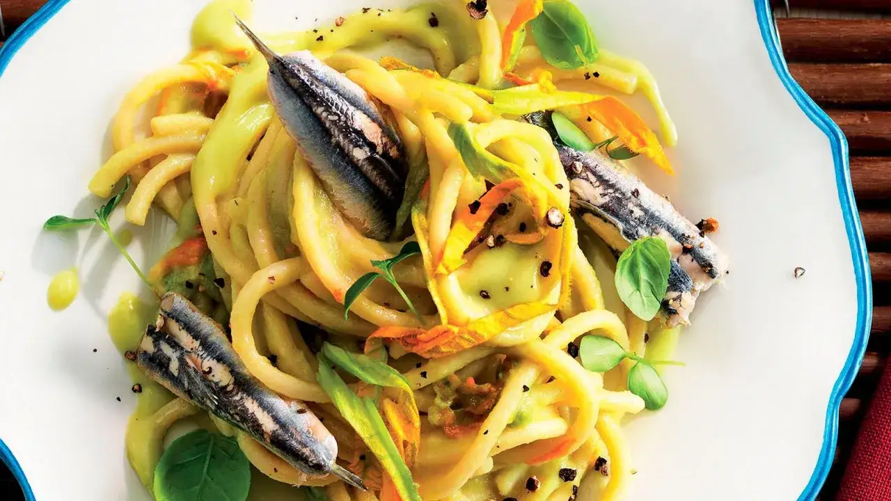Pasta con fiori di zucca e alici, un piatto estivo colorato e saporito, con erbe fresche e pepe nero.