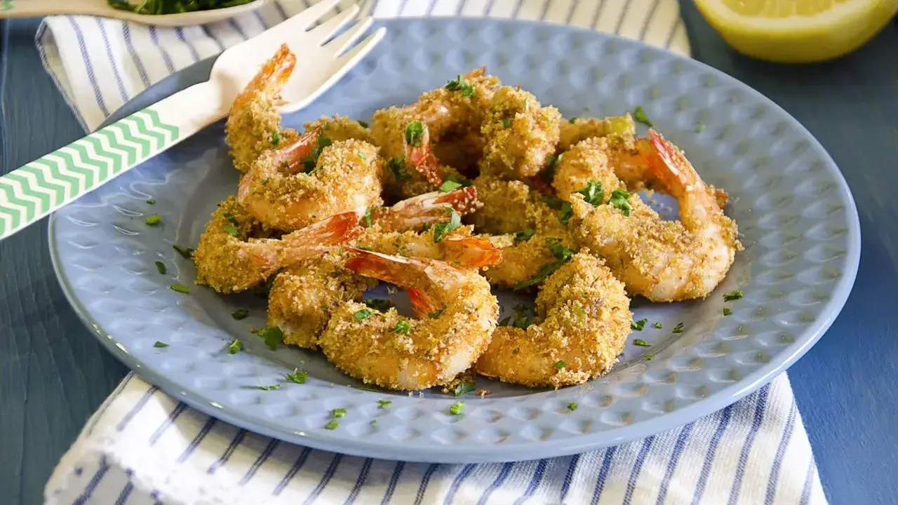 Gamberoni in padella dorati e croccanti, guarniti con prezzemolo fresco. Un piatto invitante pronto per essere gustato.