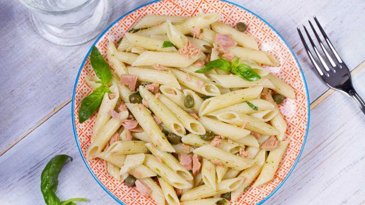 Piatto di pasta tonno e limone con capperi e basilico, pronto per essere gustato.