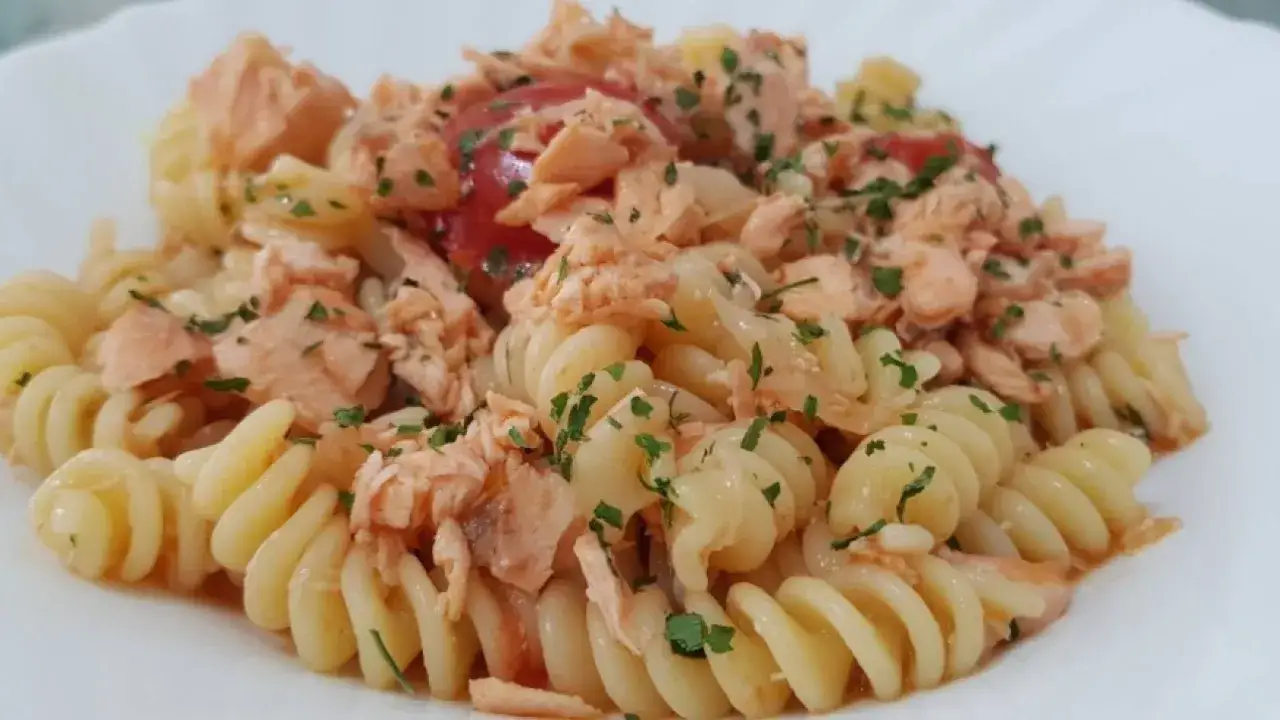 Fusilli con gustoso salmone fresco e pomodorini, guarniti con prezzemolo tritato. Un piatto semplice e delizioso.