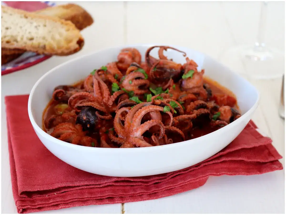 Un invitante piatto di moscardini in umido, con tentacoli succulenti e profumati, guarnito con prezzemolo fresco. Perfetto con pane croccante.