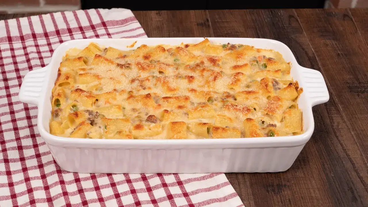 Piatto di pasta al forno bianca, con maccheroni, piselli e ragù, gratinata al forno.