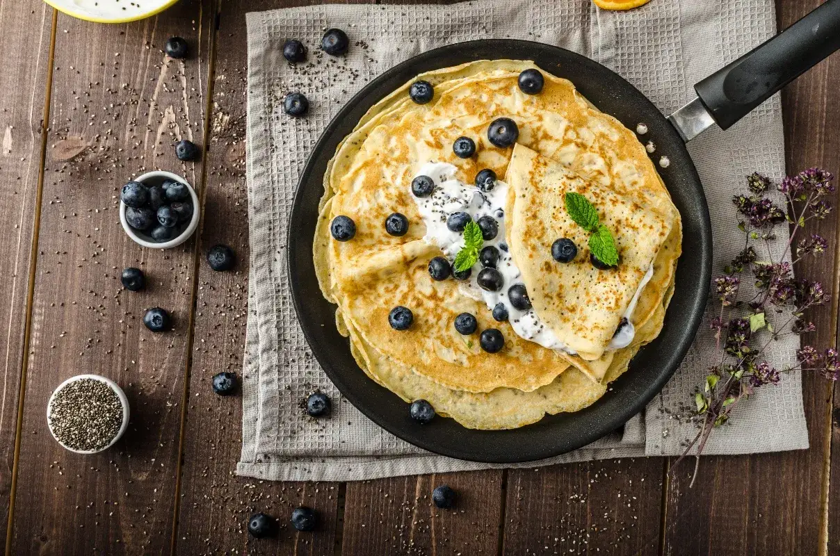 Deliziose crepes senza glutine con mirtilli freschi e yogurt, un piacere per gli occhi e per il palato.