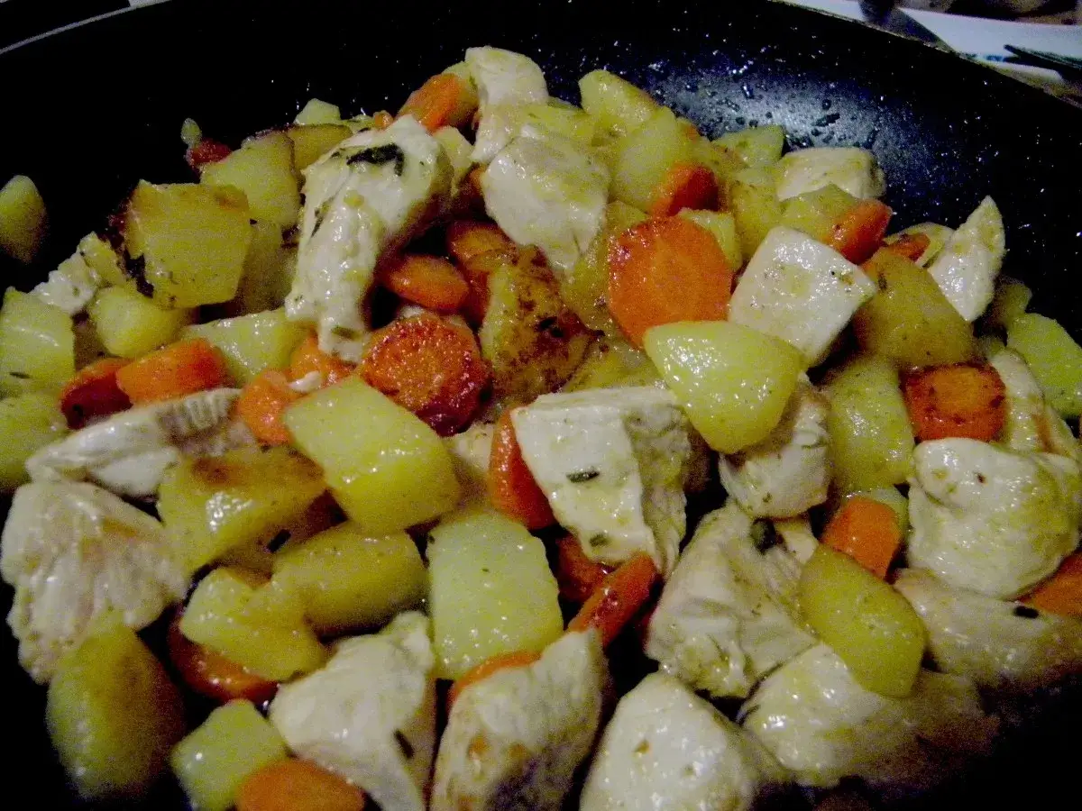 Un saporito spezzatino di pollo con patate e carote cotto in padella, pronto per essere gustato.