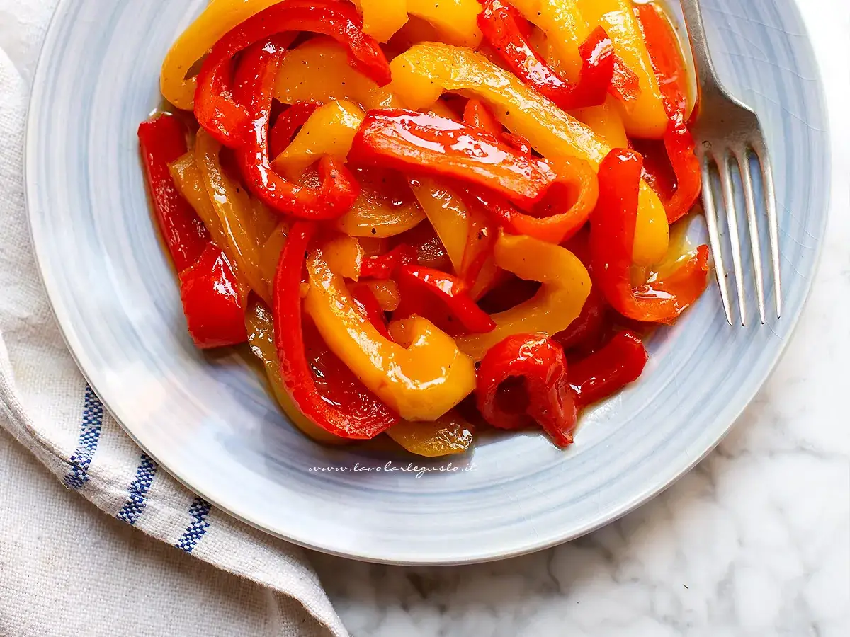 Peperoni in agrodolce, un contorno colorato e saporito, servito su un piatto azzurro con una forchetta.