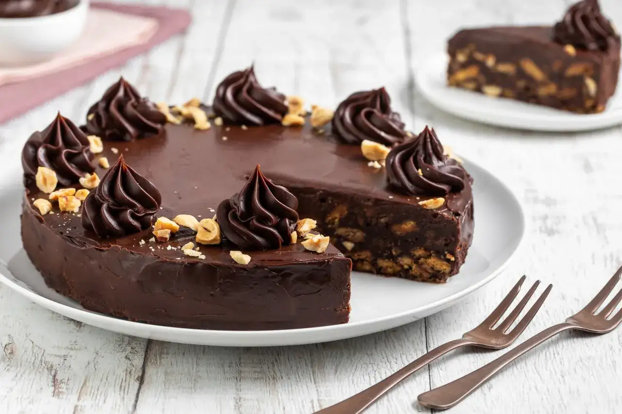 Un goloso budino al cioccolato, decorato con ciuffi di crema e nocciole tritate, pronto per essere gustato.