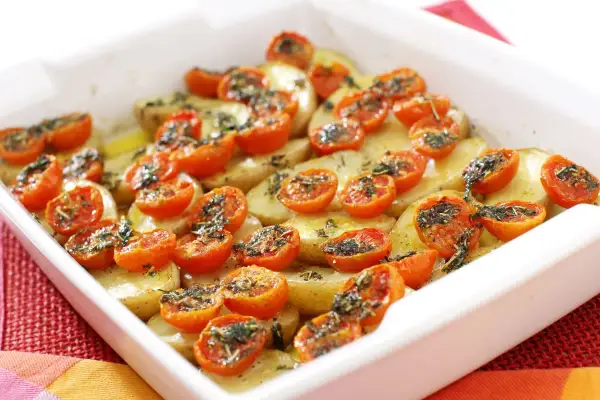 Pomodori gratinati al forno con patate, un piatto semplice e gustoso, pronto per essere infornato.