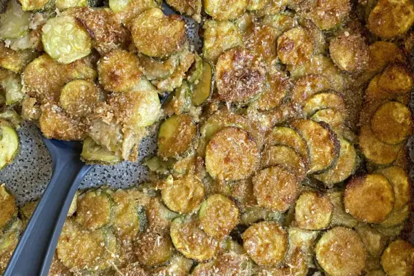 Fette di zucchine al forno dorate e croccanti, condite con parmigiano e pangrattato. Un contorno delizioso e facile da preparare.