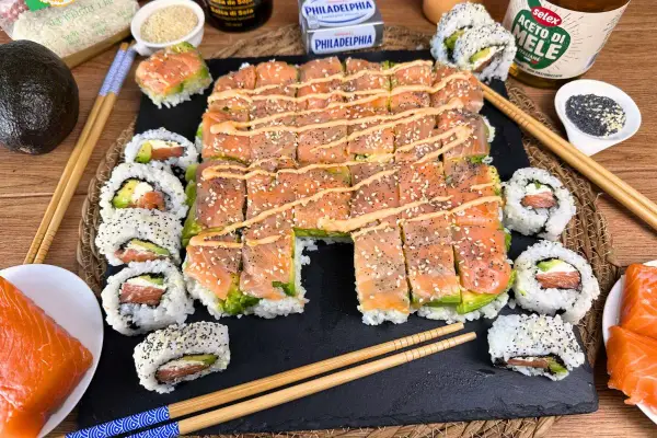 Un invitante sushi fatto in casa con salmone, avocado e formaggio Philadelphia, guarnito con semi di sesamo e una salsa cremosa.