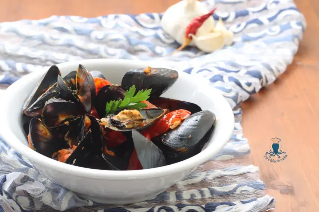 Un invitante piatto di cozze alla tarantina, con pomodorini e prezzemolo fresco, pronto per essere gustato.