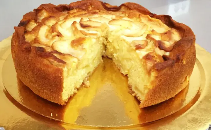 Una deliziosa torta di mele, dorata e soffice, con fette di mela disposte a spirale sulla superficie.