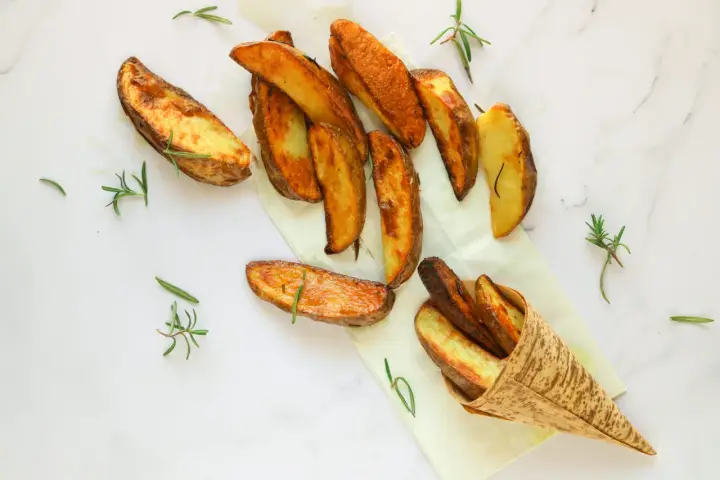Patate al forno dorate e croccanti, guarnite con rametti di rosmarino fresco. Un piacere per gli occhi e per il palato.
