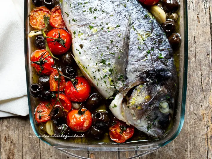 Orata al forno con pomodorini e olive nere, un piatto saporito e profumato, pronto per essere gustato.